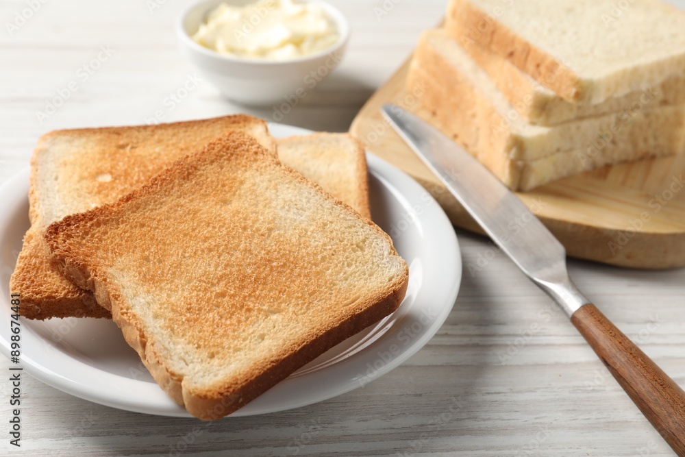 Delicious toasted bread slices with knife on white wooden table, closeup Delicious toasted bread slices with knife on white wooden table, closeup