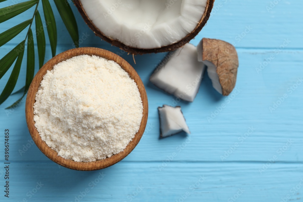 Fresh coconut flour in bowl, nut and palm leaf on light blue wooden table, flat lay Fresh coconut flour in bowl, nut and palm leaf on light blue wooden table, flat lay