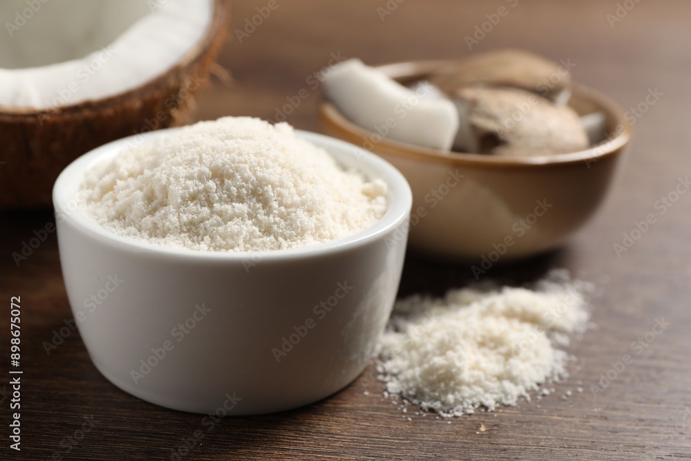 Organic coconut flour in bowl on wooden table, closeup Organic coconut flour in bowl on wooden table, closeup