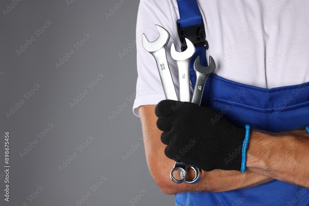 Auto mechanic with wrenches on grey background, closeup. Space for text Auto mechanic with wrenches on grey background, closeup. Space for text