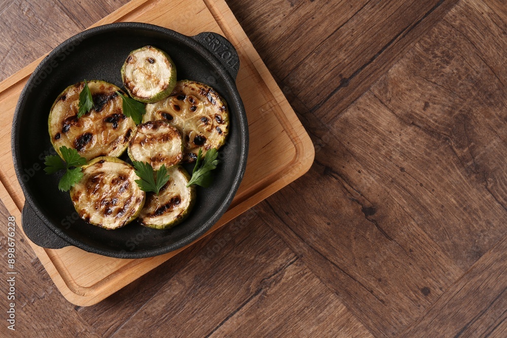 Tasty grilled zucchini slices with parsley in dish on wooden table, top view. Space for text Tasty grilled zucchini slices with parsley in dish on wooden table, top view. Space for text