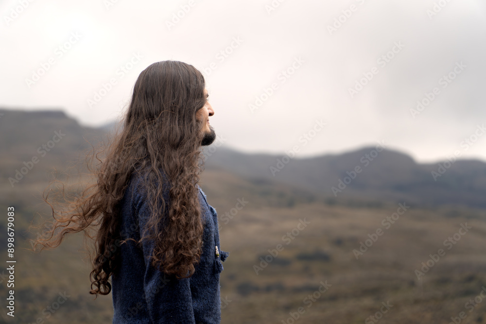 latin man traveler with long hair, beard and glasses admiring nature wearing clothes that have indigenous patterns latin man traveler with long hair, beard and glasses admiring nature wearing clothes that have indigenous patterns