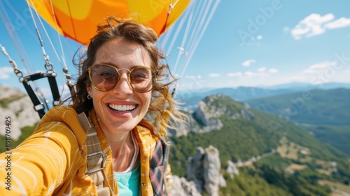 A thrill-seeking woman enjoys paragliding over picturesque mountains, smiling as she soars through the sky. She is equipped with a colorful parachute and protective gear.