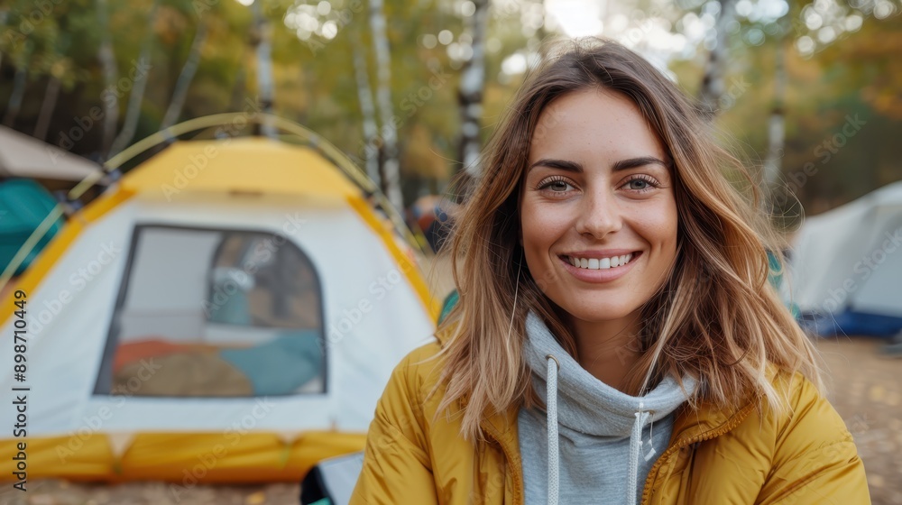 A woman smiles warmly in an outdoor camping setting, seated in front of a yellow tent, wearing casual camping attire, showcasing the joys of outdoor adventures. A woman smiles warmly in an outdoor camping setting, seated in front of a yellow tent, wearing casual camping attire, showcasing the joys of outdoor adventures.