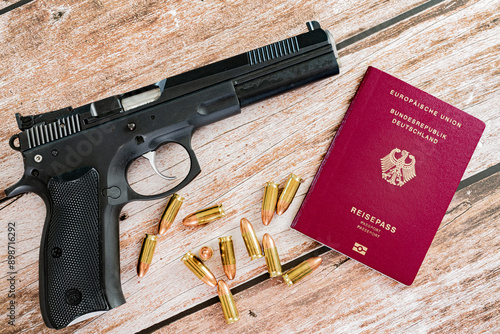 black pistol with 9 mm bullets and german travel passport on wooden plank background photo