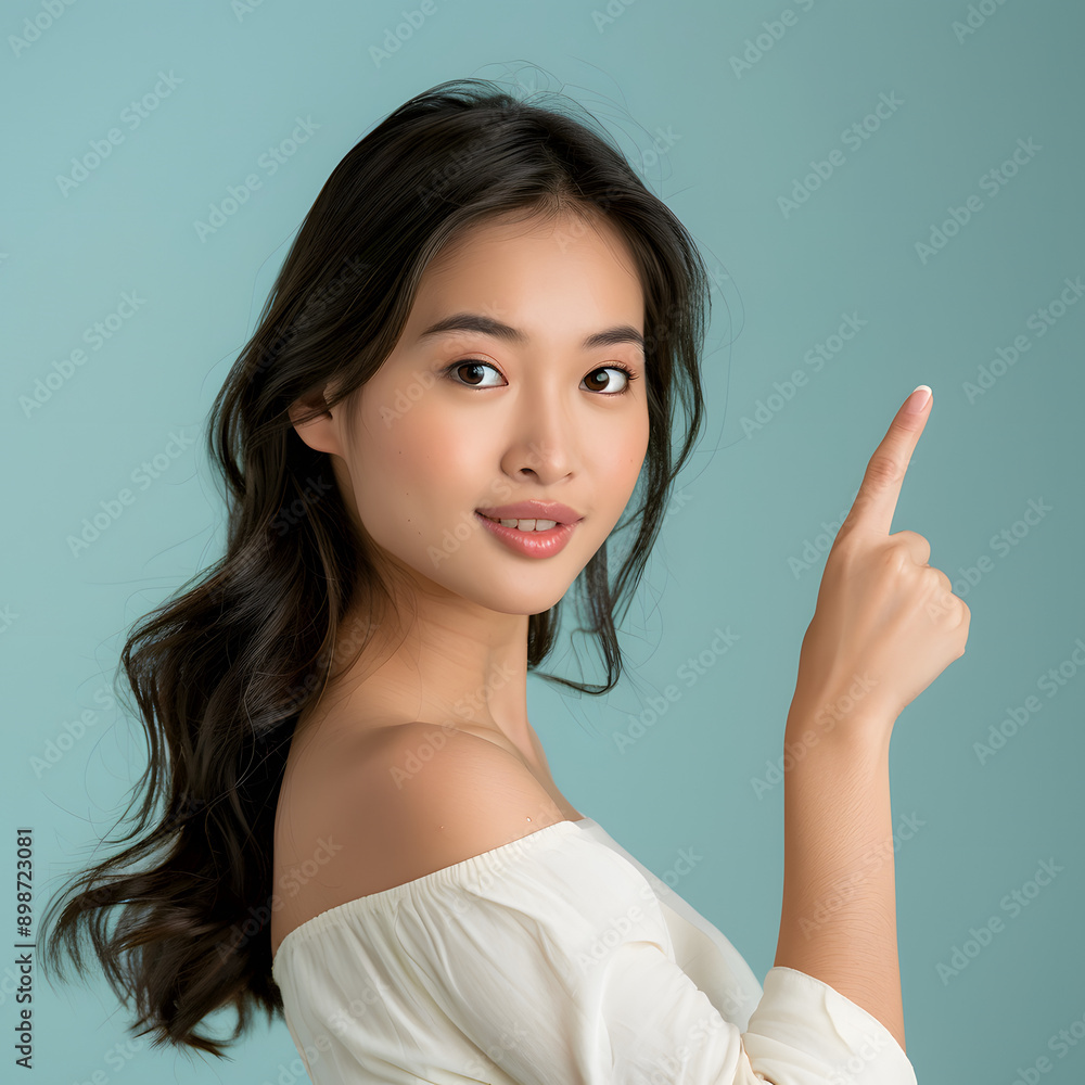 Asian woman presents, pointing with copy space light blue background, portrait captures the beauty, confidence, and elegance of a young and attractive Asian model. Asian woman presents, pointing with copy space light blue background, portrait captures the beauty, confidence, and elegance of a young and attractive Asian model.