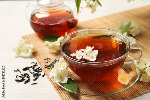 Hot jasmine tea in cup and flowers on white wooden table