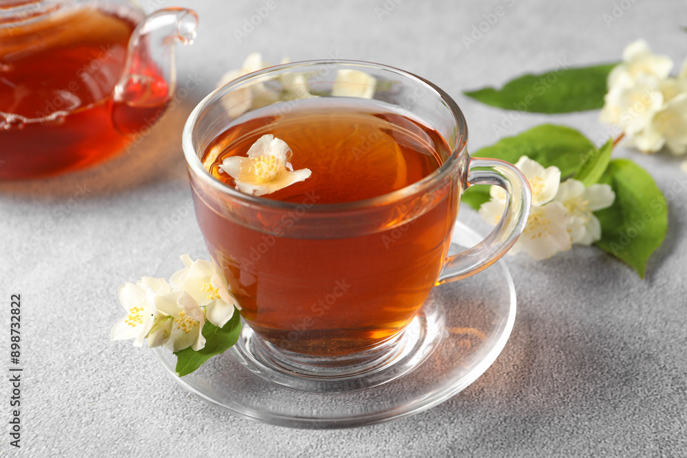 Hot jasmine tea in cup and flowers on light grey table Hot jasmine tea in cup and flowers on light grey table