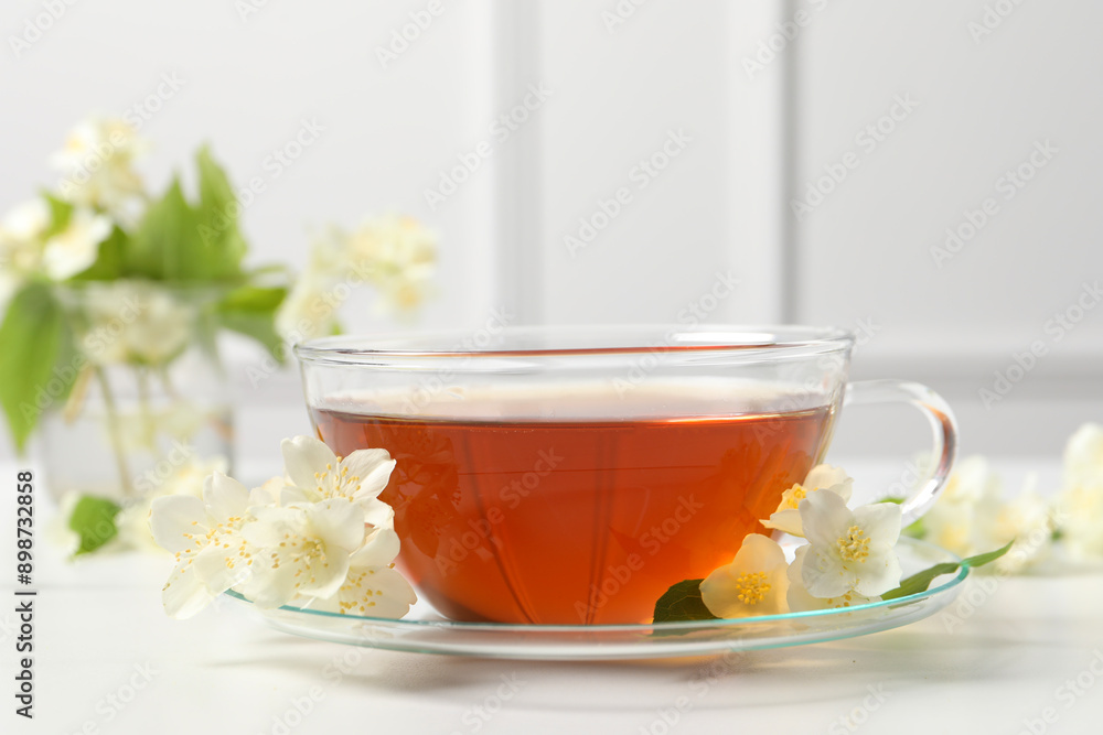 Hot jasmine tea in cup and flowers on white marble table Hot jasmine tea in cup and flowers on white marble table