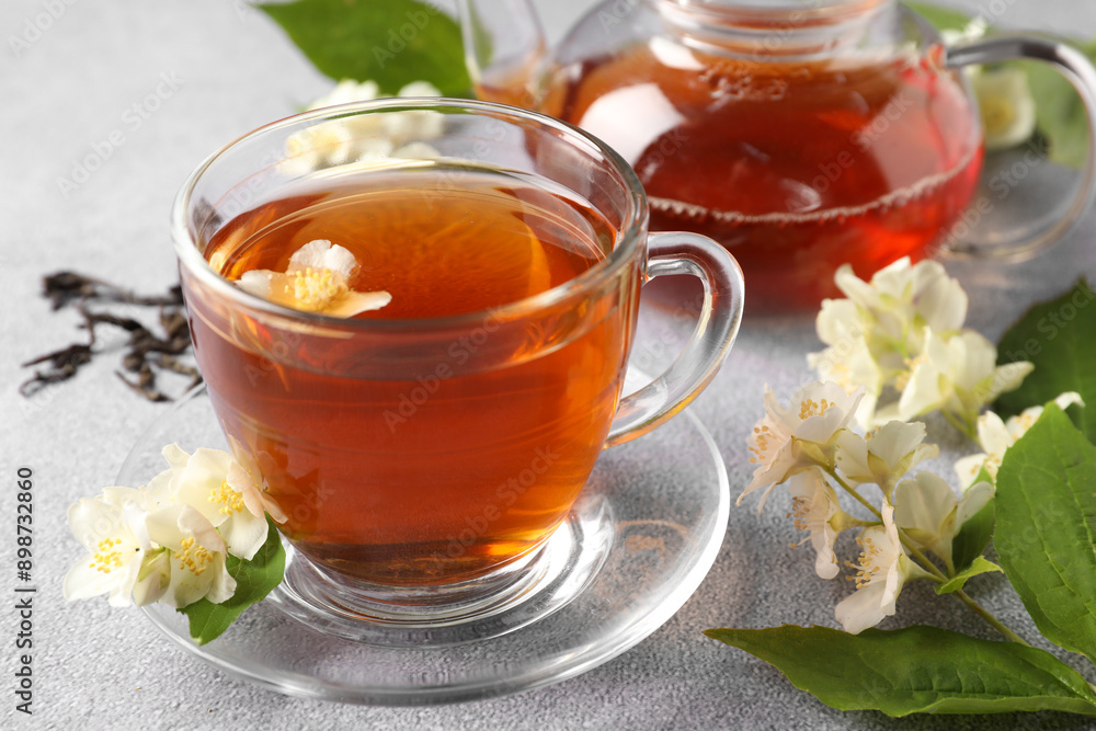 Hot jasmine tea in cup and flowers on light grey table Hot jasmine tea in cup and flowers on light grey table
