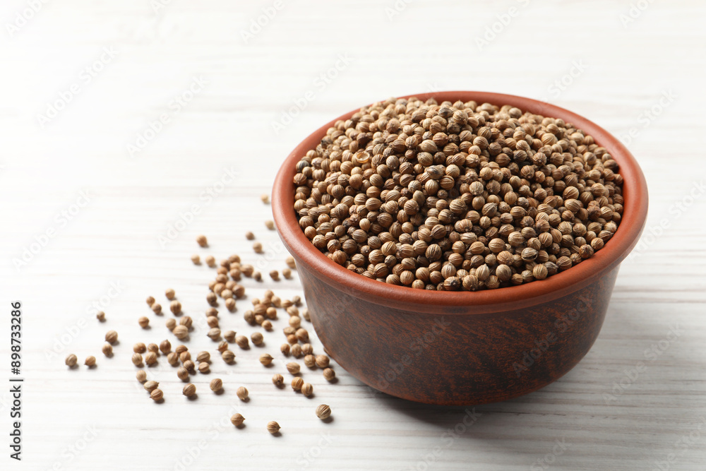 Dried coriander seeds in bowl on wooden table Dried coriander seeds in bowl on wooden table