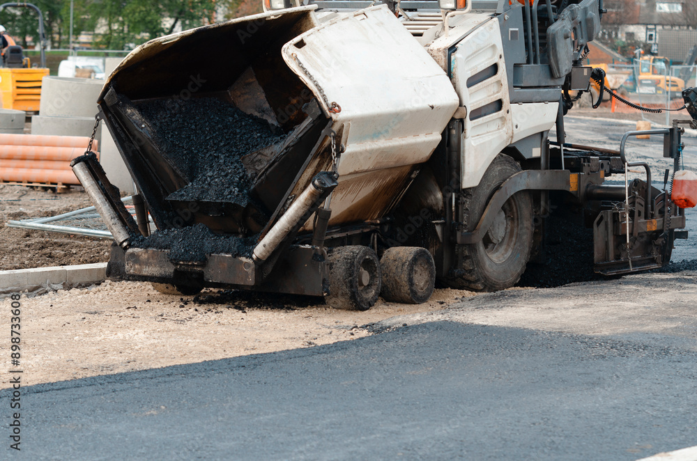 Asphalt Paver Machine Laying Down Fresh Asphalt on Construction Site During Daylight Hours Asphalt Paver Machine Laying Down Fresh Asphalt on Construction Site During Daylight Hours