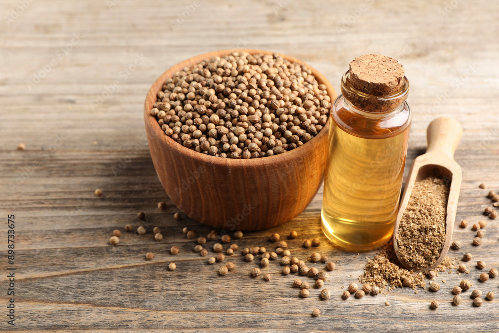 Coriander essential oil, powder and seeds on wooden table Coriander essential oil, powder and seeds on wooden table