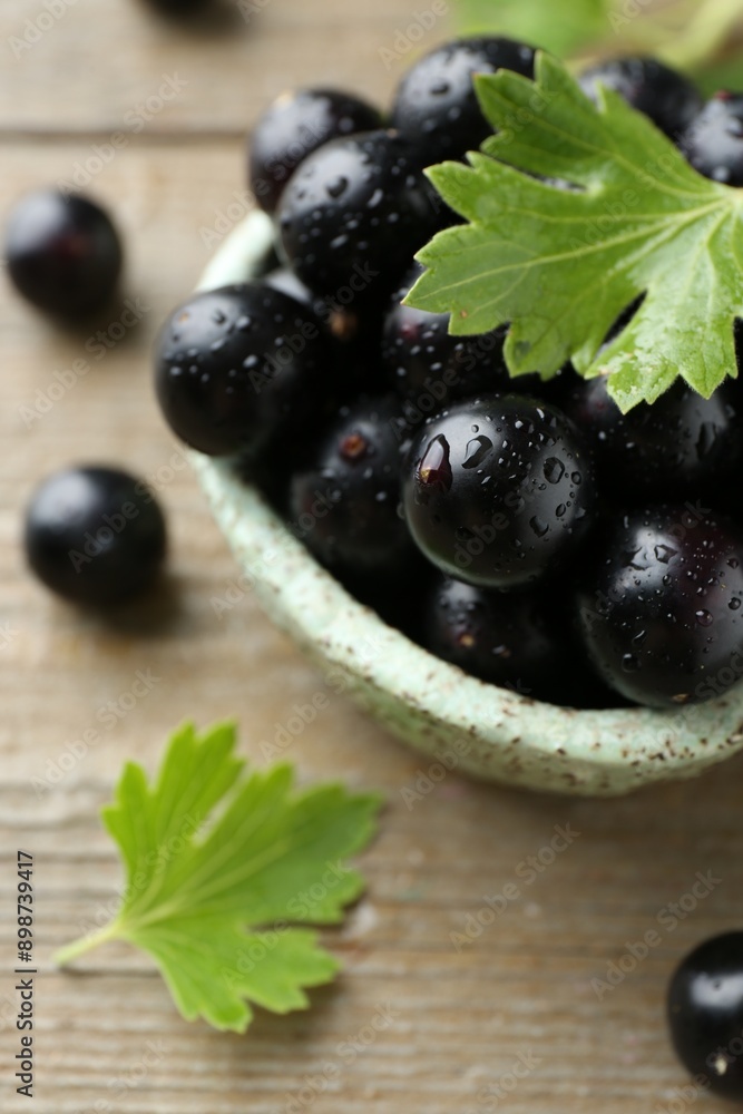 Fresh ripe black currant berries and leaves on wooden table, closeup Fresh ripe black currant berries and leaves on wooden table, closeup