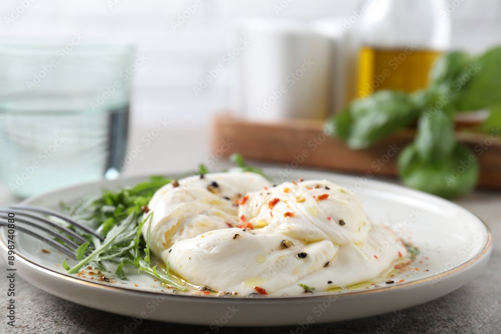 Delicious burrata cheese, arugula and spices on grey table, closeup Delicious burrata cheese, arugula and spices on grey table, closeup