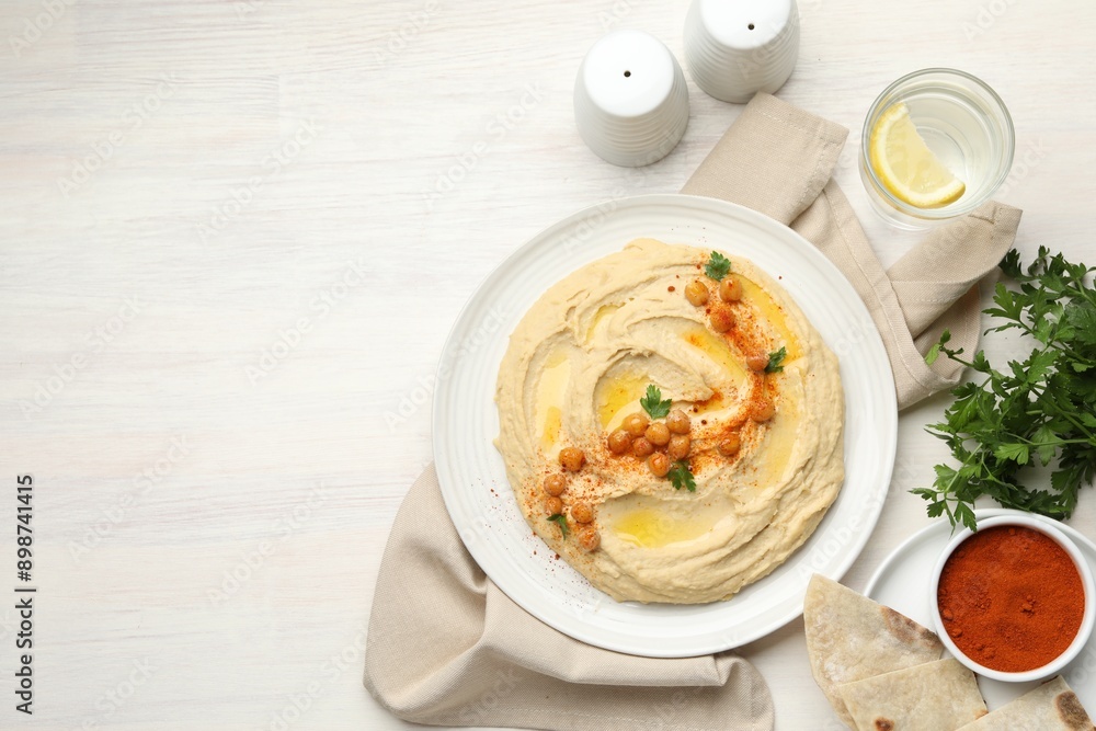 Delicious hummus with olive oil, chickpeas and paprika served on white wooden table, flat lay. Space for text Delicious hummus with olive oil, chickpeas and paprika served on white wooden table, flat lay. Space for text