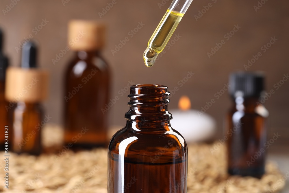 Essential oil dripping from pipette into bottle at table, closeup Essential oil dripping from pipette into bottle at table, closeup