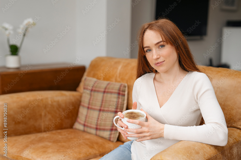 Young Woman Sipping Coffee On A Leather Sofa In A Living Room Young Woman Sipping Coffee On A Leather Sofa In A Living Room