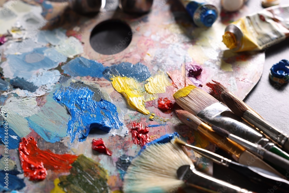 Artist's palette, brushes and paints on grey table, closeup Artist's palette, brushes and paints on grey table, closeup