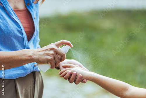 Cuadro en lienzo A Caucasian woman sprays mosquito repellent on her young daughter's arm, preparing for a day in the natural setting