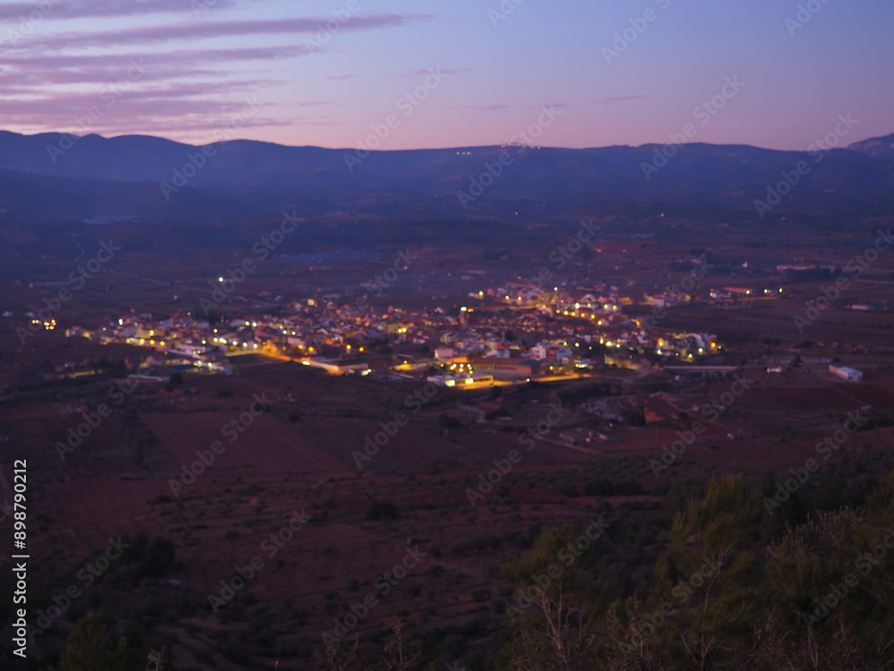 Obraz premium Adzaneta del Maestre, a village in El Maestrazgo, in the Province of Castellón, Spain, illuminated at night, from the mountains of El Bovalar