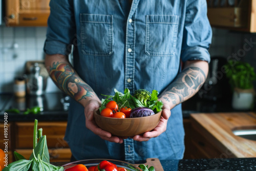 Tattoed man holding bowl with vegetables