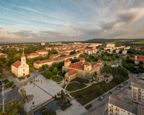 Aerial view of Varpalota Thury castle with newly renovated red orange roof, four rectangular towers in the middle of the former mining town with communist block houses in the background. photo