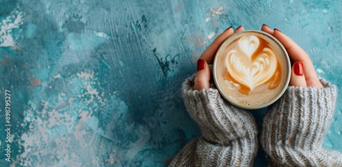 Womans Hands Holding a Cup of Latte Art on a Blue Background