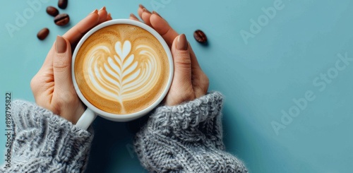 Womans Hands Holding a Cup of Latte Art on a Blue Background