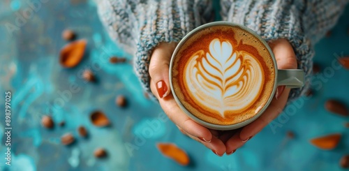 Womans Hands Holding a Cup of Latte Art on a Blue Background