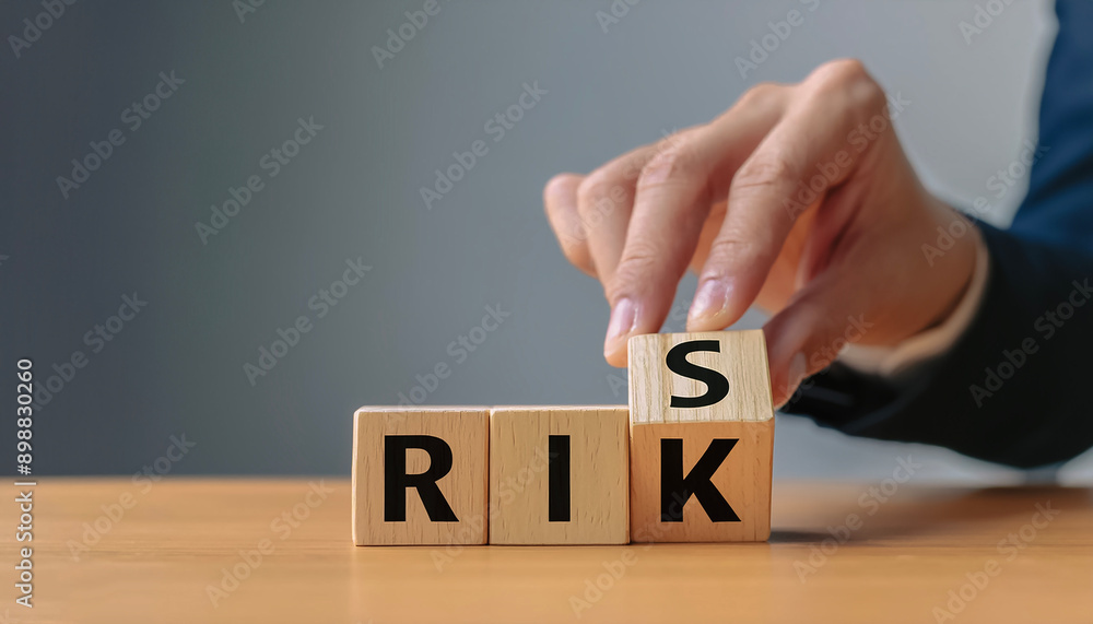 Naklejka premium Risk management concept. Businessman hand put risk word on wooden block cube for financial banking analysis and business management.