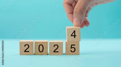 Hand changing wooden block to 2025 for newyear concept on plain background.