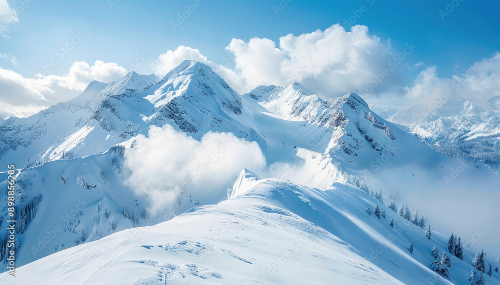 Obraz premium A snowcovered mountain with clouds on a sunny day under a clear sky creates a picturesque scene