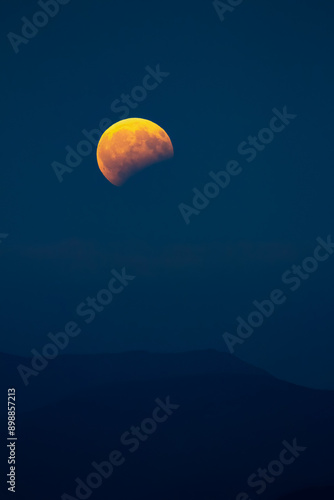 A partial eclipse of the Moon rising over the land.