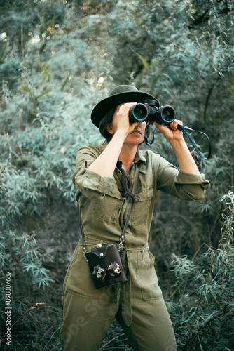 Canvas Print Female traveler with binoculars in her hands is looking at animals in the thickets