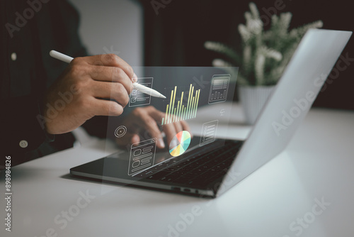 Person using a stylus on a laptop with floating charts and data visualizations. It represents the use of digital tools for data analysis, business intelligence in a modern work environment. photo