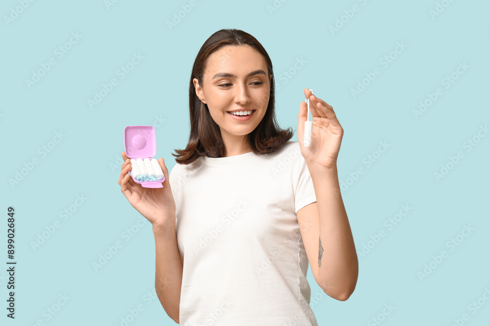 Beautiful young woman with tampons storage box on blue background Beautiful young woman with tampons storage box on blue background