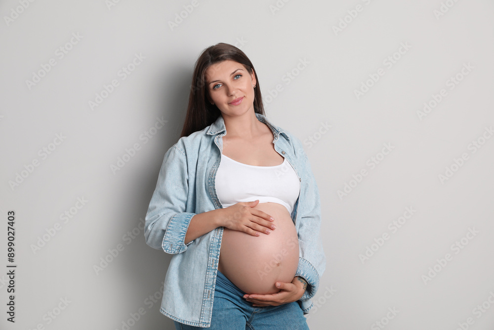 Portrait of beautiful pregnant woman on gray background
