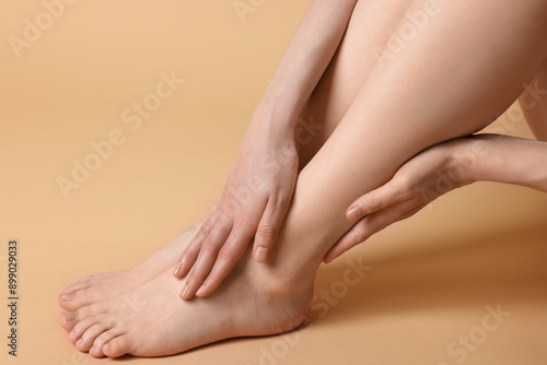 Closeup view of woman`s groomed feet after care procedure on beige background