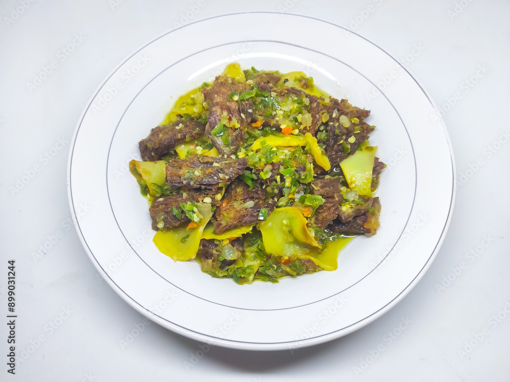Jerado cabe hijau or Dendeng is a traditional cuisine from west sumatera, indonesia. it is made from slice of beef with spicy sauce called sambal. served on plate and isolated white background Jerado cabe hijau or Dendeng is a traditional cuisine from west sumatera, indonesia. it is made from slice of beef with spicy sauce called sambal. served on plate and isolated white background