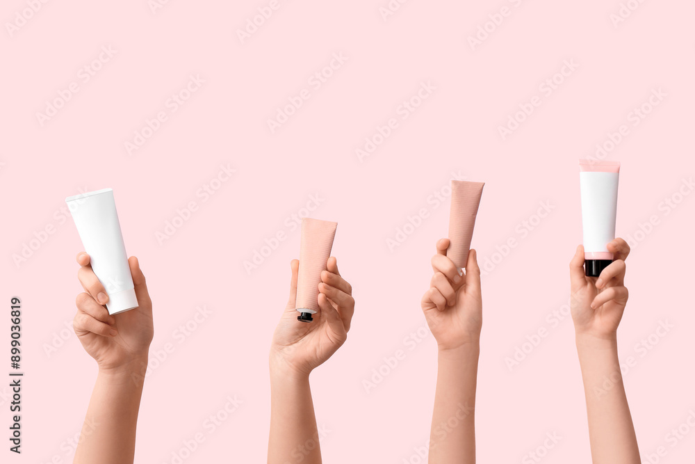 Female hands with tubes of different cosmetic cream on pink background Female hands with tubes of different cosmetic cream on pink background