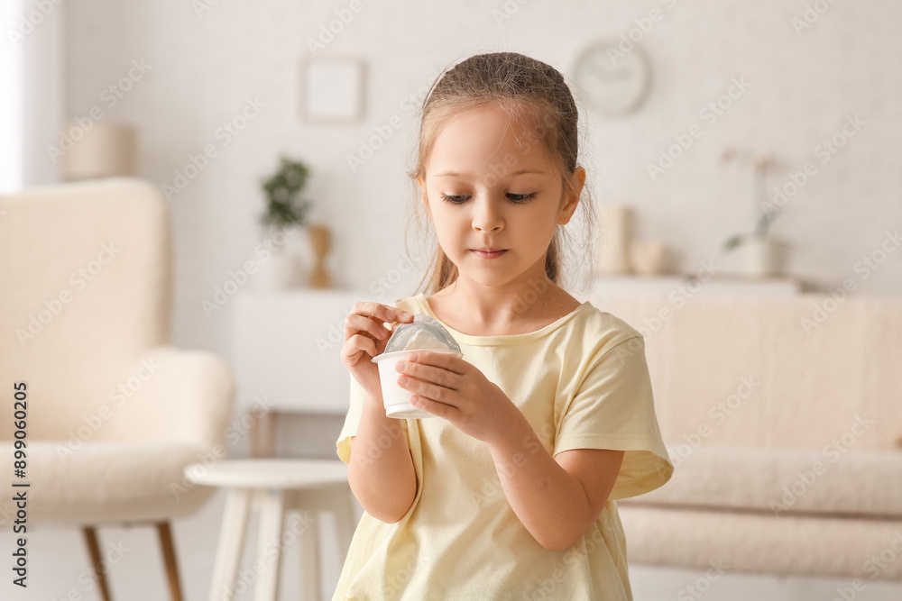 Cute little girl opening yogurt pack at home Cute little girl opening yogurt pack at home