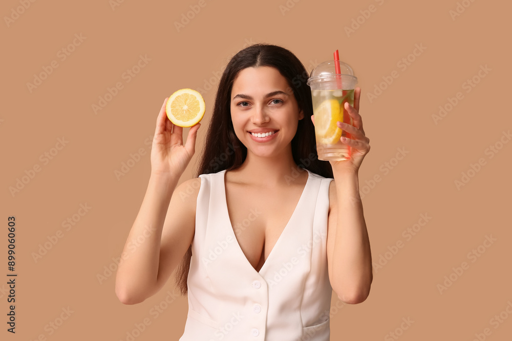 Beautiful young happy woman with lemon half and cup of fresh lemonade on beige background Beautiful young happy woman with lemon half and cup of fresh lemonade on beige background