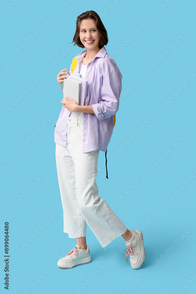 Beautiful female student with books on blue background Beautiful female student with books on blue background