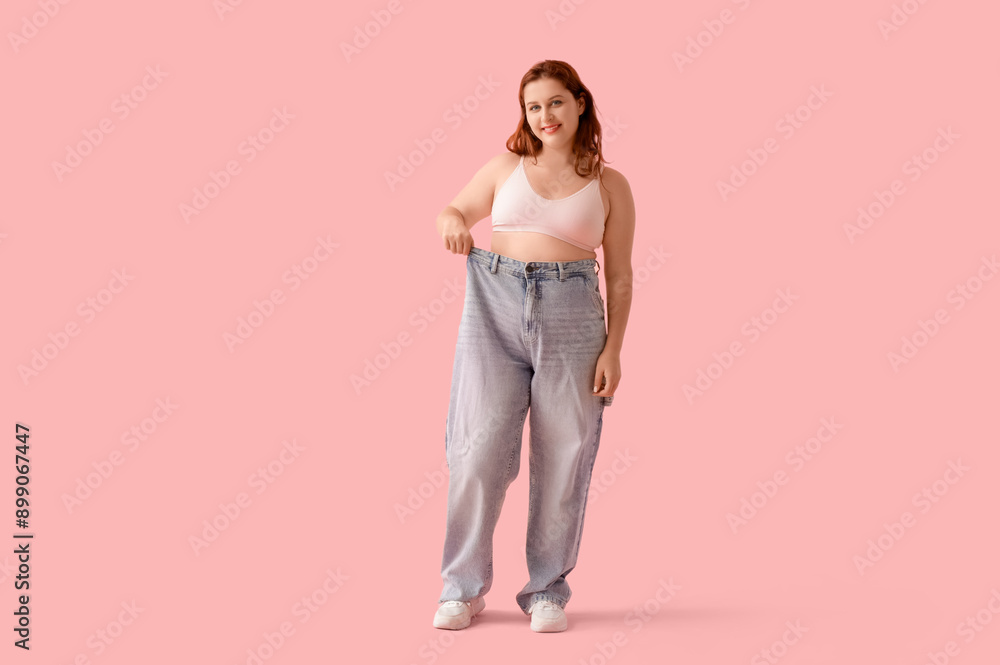 Overweight young happy woman in loose jeans on pink background. Weight gain concept Overweight young happy woman in loose jeans on pink background. Weight gain concept