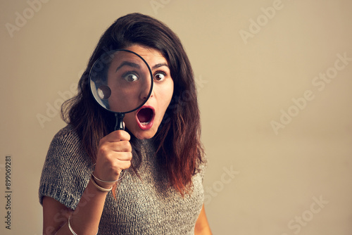 Foto Girl, portrait and surprise with magnifying glass in studio for investigation on bargain for price saving and retail discount