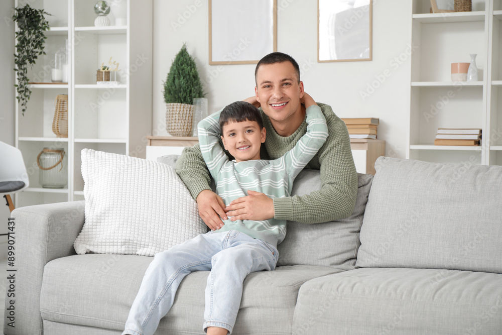 Cute little boy with his father hugging on sofa at home Cute little boy with his father hugging on sofa at home