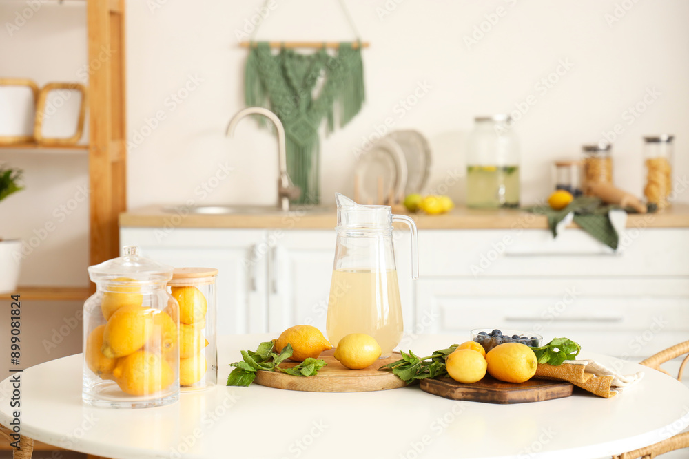 Jug of lemonade with lemons and mint on table in kitchen Jug of lemonade with lemons and mint on table in kitchen