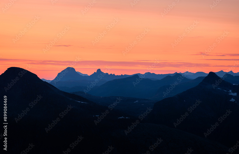 Panorama of silhouettes of mountains seen from Tortenviktind. Summer midnight sun view over Svartisen nationalpark and saltfjellet. Fjelltur natt i Norge. Twilight and golden hour with blue mountains Panorama of silhouettes of mountains seen from Tortenviktind. Summer midnight sun view over Svartisen nationalpark and saltfjellet. Fjelltur natt i Norge. Twilight and golden hour with blue mountains