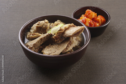 Close-up of Galbitang(Short Rib Soup) with Kkakdugi(cubed radish kimchi) on jars and cloth floor, South Korea 